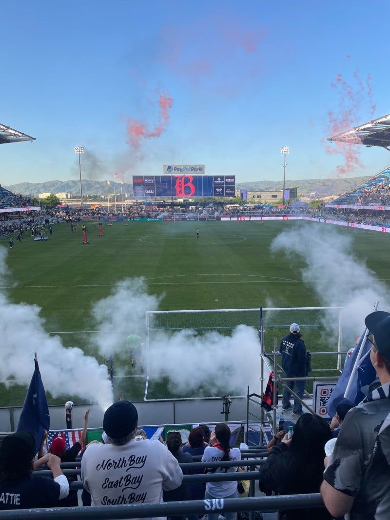 Smoke rises from the crowd at a soccer stadium.