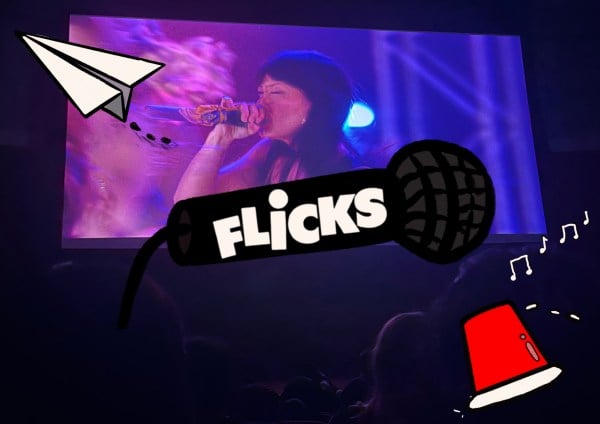 Microphone reading "FLiCKS" on it with a paper airplane and a red cup around it. Int he background an image of the screening at CEMEX.