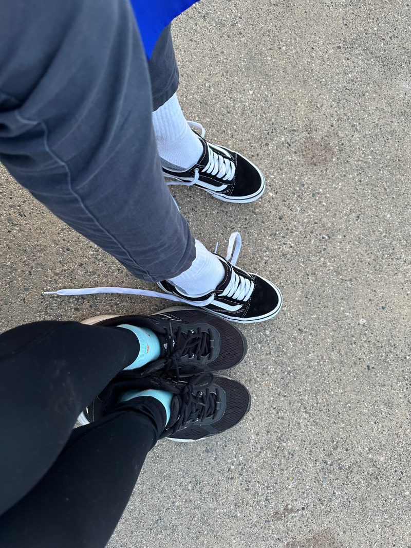 A photo of two people's legs and shoes.