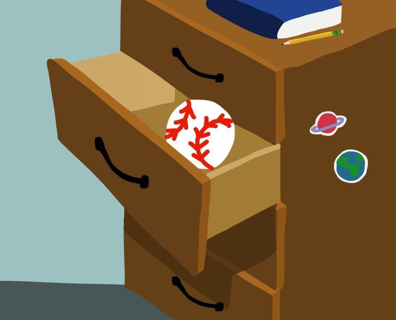 A baseball sits in an open desk drawer.