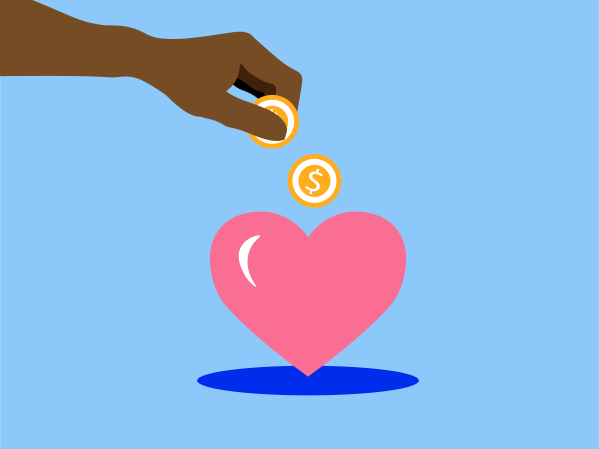 A hand drops coins into a heart-shaped piggy bank