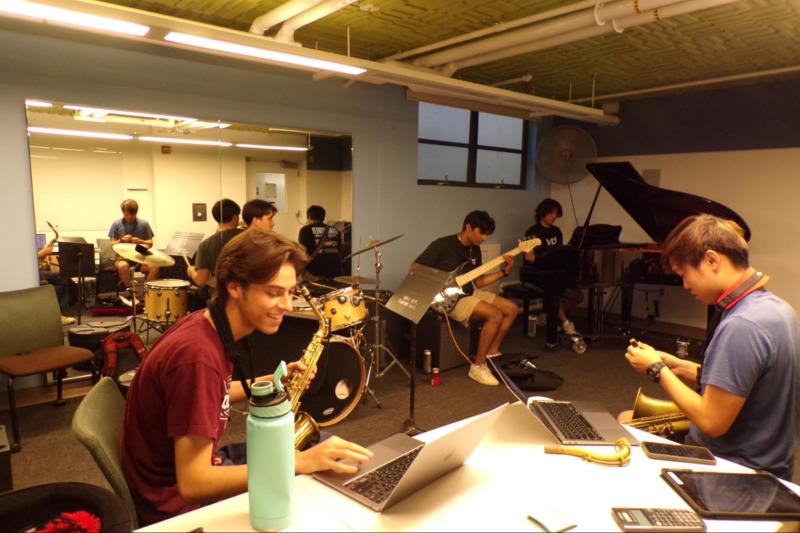 Five members of "The Move" sit in a rehearsal room with instruments, practicing for their opening set at Frost Fest.