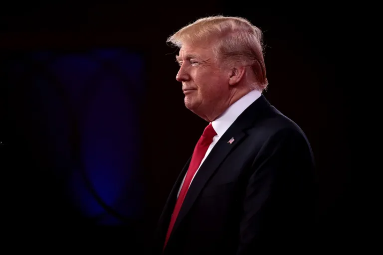 Donald Trump in profile against black background.