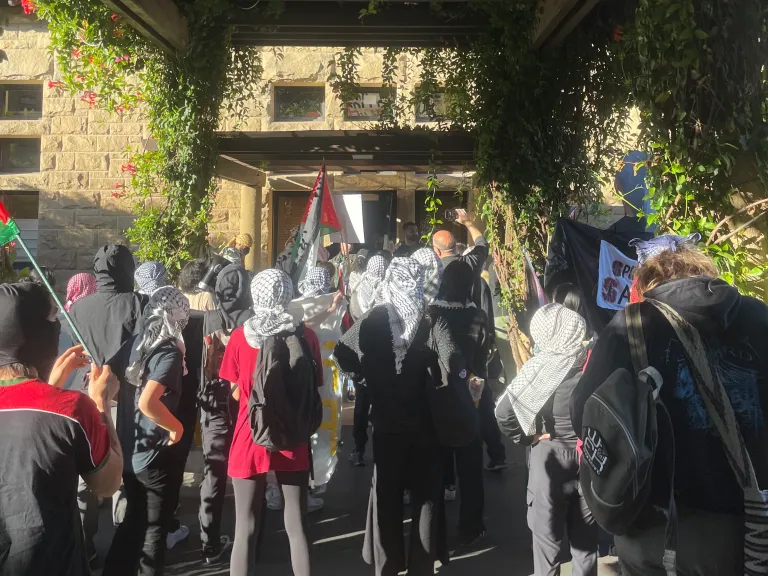 a group of pro-Palestine protesters crowd around sheriff officers detaining other students in main quad