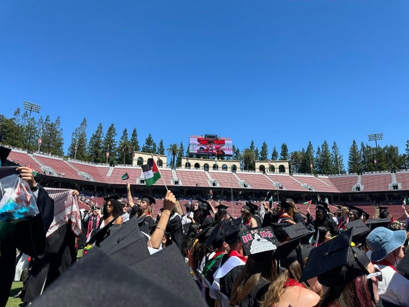 Students stand from seats in Stanford Stadium.