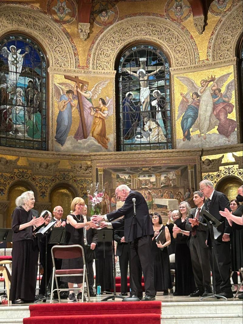 Retiring director of Early Music Singers William Mahrt accepts flowers from choir members on the stage of Memorial Church.