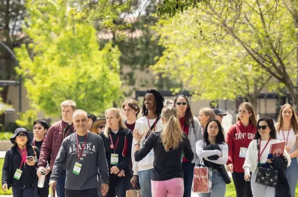 A young woman leads a tour group of several visitors on a sunny day.