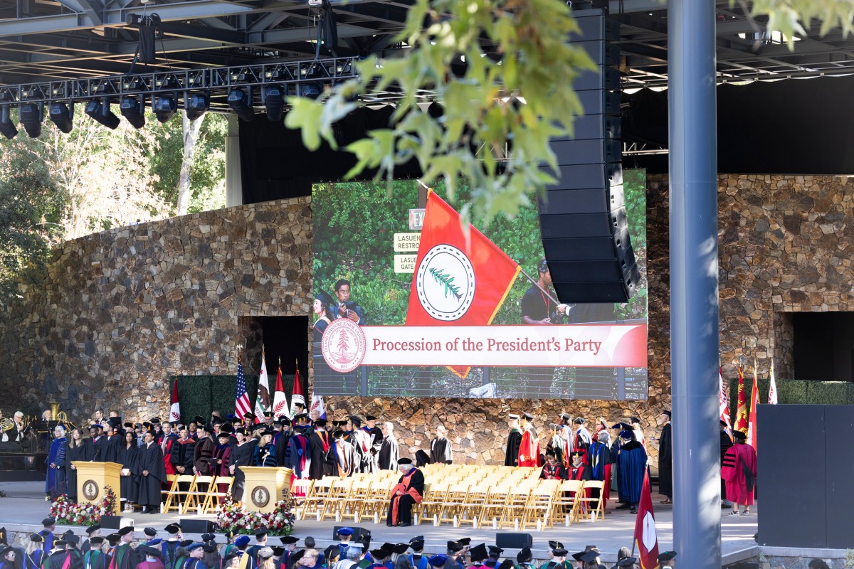 A photo of Frost Amphitheater stage, wit faculty members in robes.