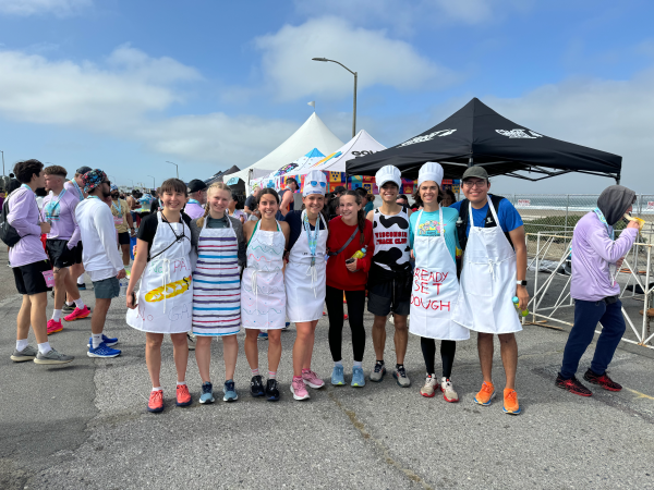 A group of costumed runners stand by a tent at the end of a race.