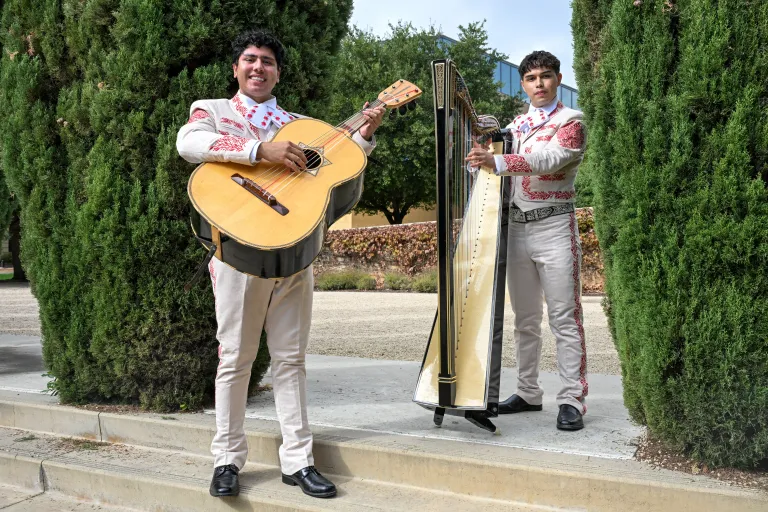 Carlos Pardo ’27 and Patrick Vasquez ’27 hold their instruments and stand on the steps of the Cantor Arts Center.