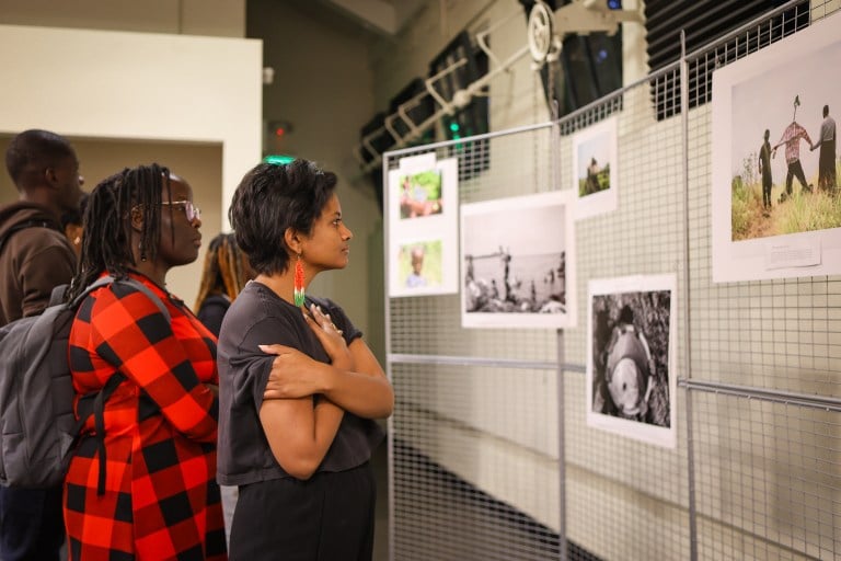 Two students stand and look at a photo gallery