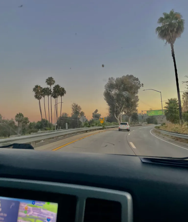 A California sunset from the view of a car front window.