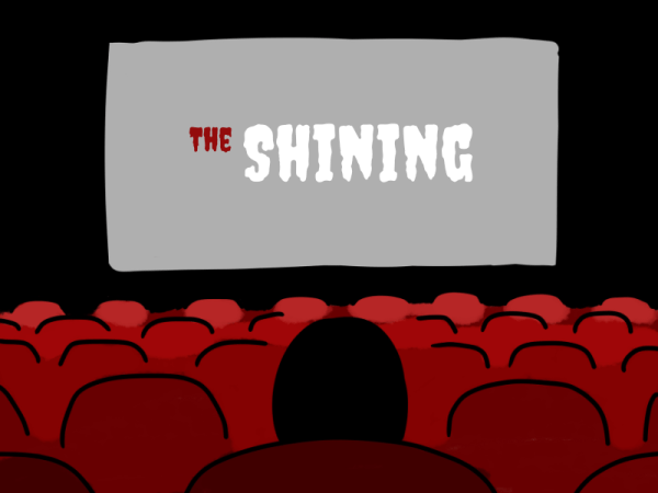 A person sits in a movie theater with the text "The Shining" on the screen.