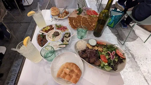 An array of Mediterranean food, Turkish pizza, a variety of appetizers and a plate of meat.