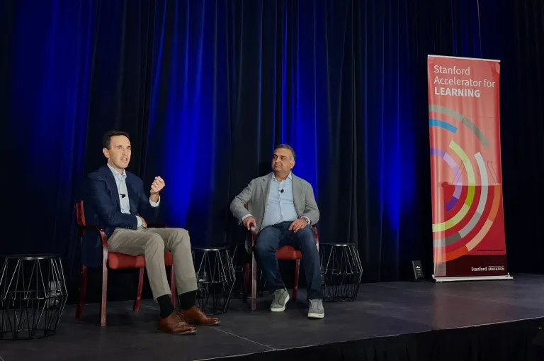 Stanford president Jon Levin ’94, left, and Neal Mohan ’96 MBA ’05 sit on stage and speak at an edtech summit discussing the roles of technology and AI in education.