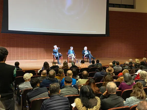 Alan Lightman and moderators sit together on stage in front of audience.