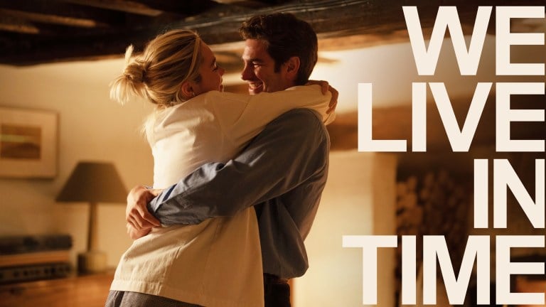 A man and a woman hug each other, with the text "We Live in Time" next to them.