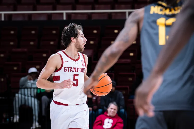 Stanford men's basketball player dribbles ball.