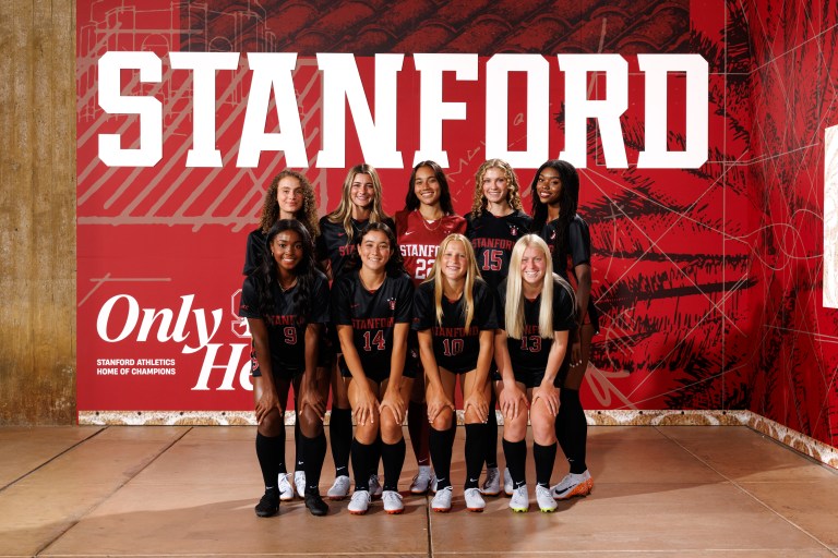 Women's soccer players smile for a photo.