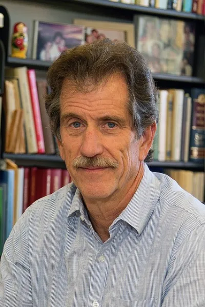 A headshot of Professor Paul Segall with a bookshelf behind him.