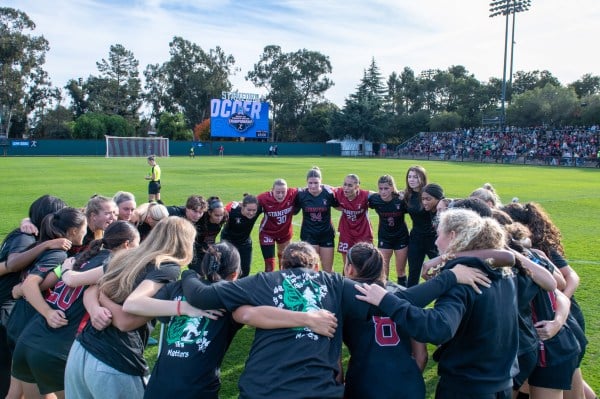 Soccer players stand in circle.