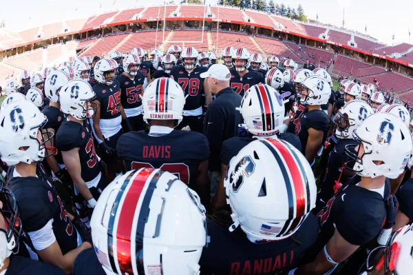 Football team stands in huddle.