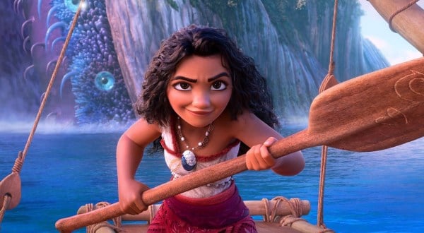 A girl (Moana, the titular character) holds an oar and smiles confidently.