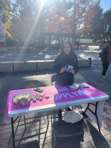 A student stands behind a table in White Plaza.