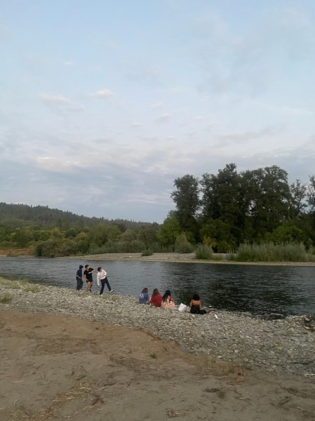 Students sit and stand along a riverbed in Oregon.