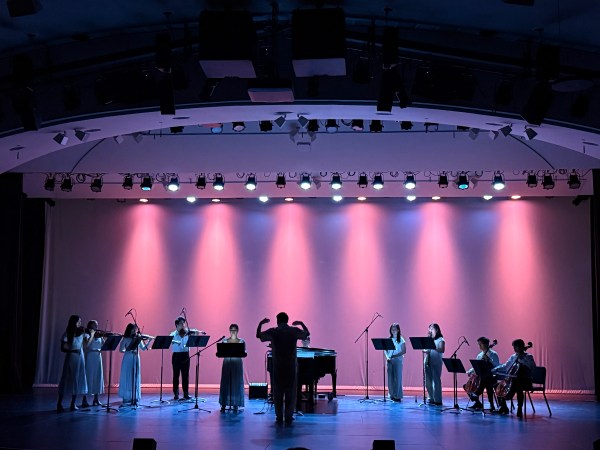 A group of Stanford musicians perform at “When the World Breathes Again” against a backdrop of pink and purple stagelights