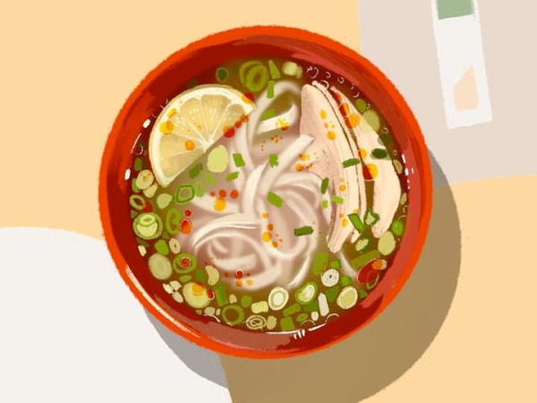 A lemon, green onions and chicken slices float in the soup of a red bowl of Wilbur pho.