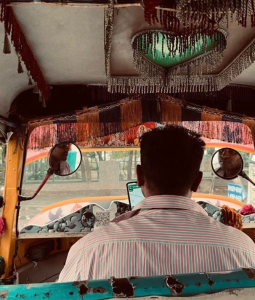 Perspective from the seat of an auto rickshaw, facing the back of the driver's head
