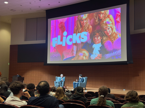 An auditorium filled with audience members for a screening of "Austin Powers." Director Jay Roach '79 and Q&A moderator Daniel Rashes ’26 sit onstage.