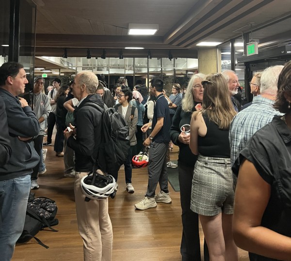 Students and faculty stand talking in the entrance to Tresidder Oak Lounge.