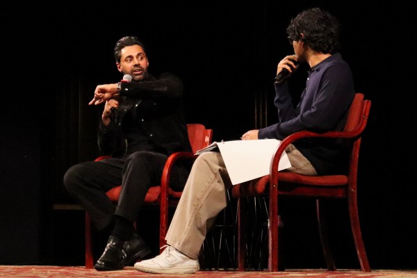 Hasan Minhaj speaks into a microphone on-stage with at a Q&A session with the Stanford Speakers Bureau at Memorial Auditorium.