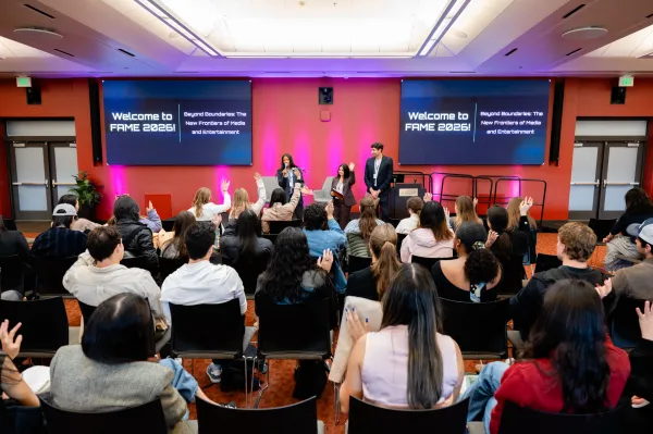 Panelists speak at the 2026 FAME Conference against a red-purple backdrop on stage.