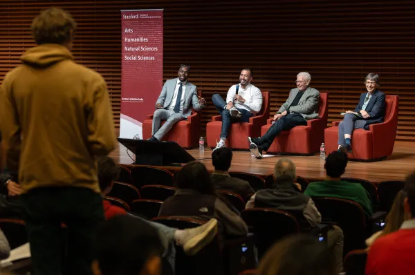 A panel of four speakers sits on stage in discussion.