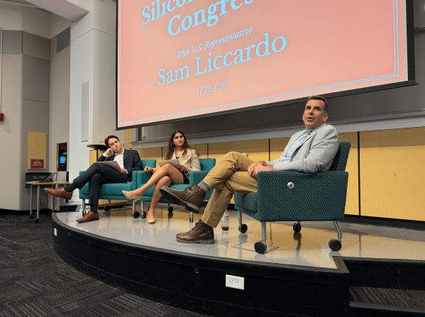 Sam Liccardo sits on stage with event moderators.