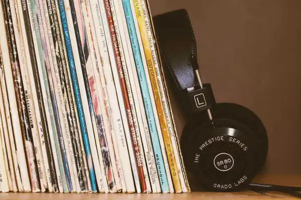 A photo of headphones leaning on a stack of records.