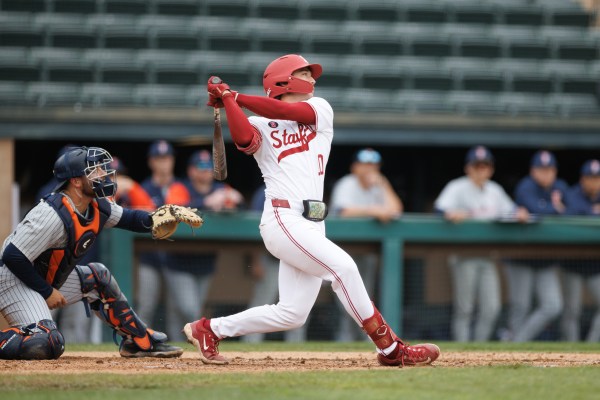 Baseball player swings at home plate.
