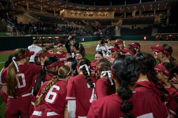 Softball players in huddle on field.