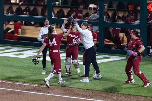 Softball teammates high-five near the dugout.