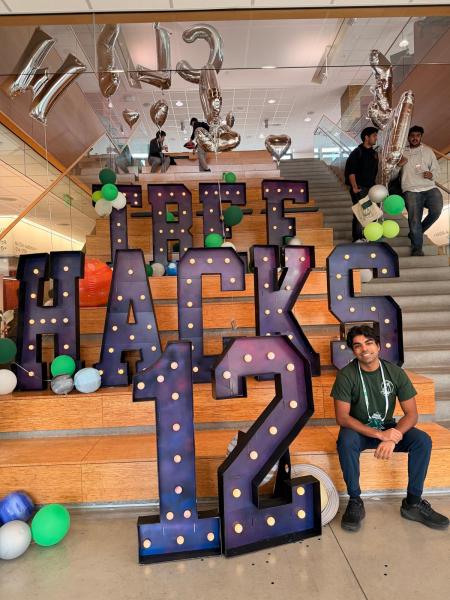 The author sitting next to large letters reading "TreeHacks 12" on the steps of Huang