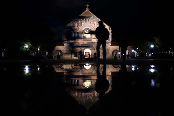 Silhouettes of people walking in front of Memorial Church on a rainy day.