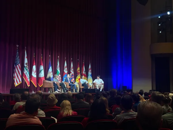 Panelists sit on stage.