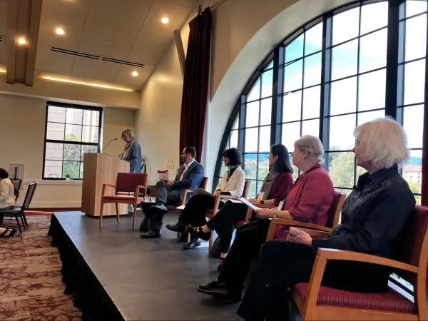 Panelists sit on a wood stage.