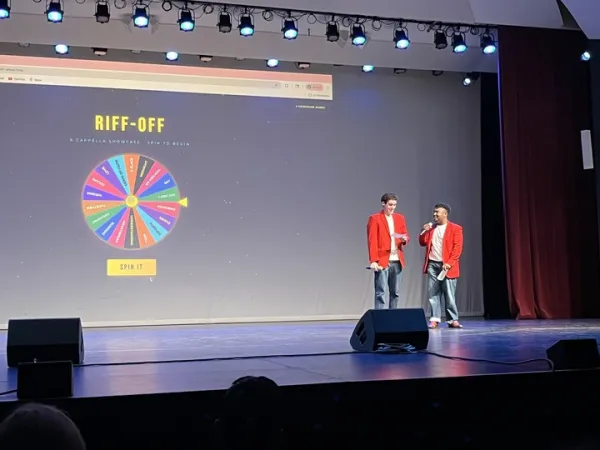 Two men wearing red jackets, standing on a stage.