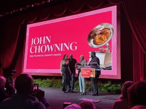 Chowning receiving a grammy award in front of a screen.
