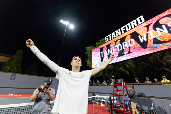 Tennis player with arms extended above head.