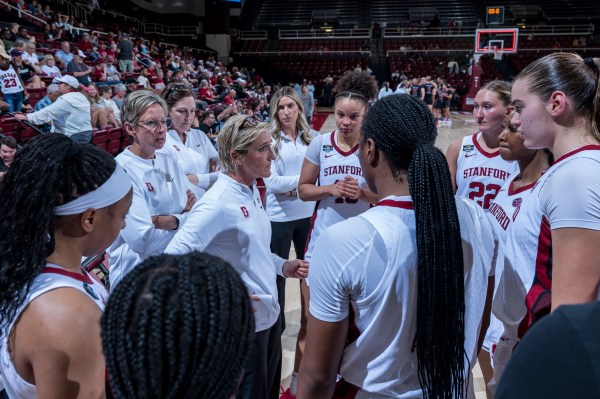 Women's basketball team stands on court during game.
